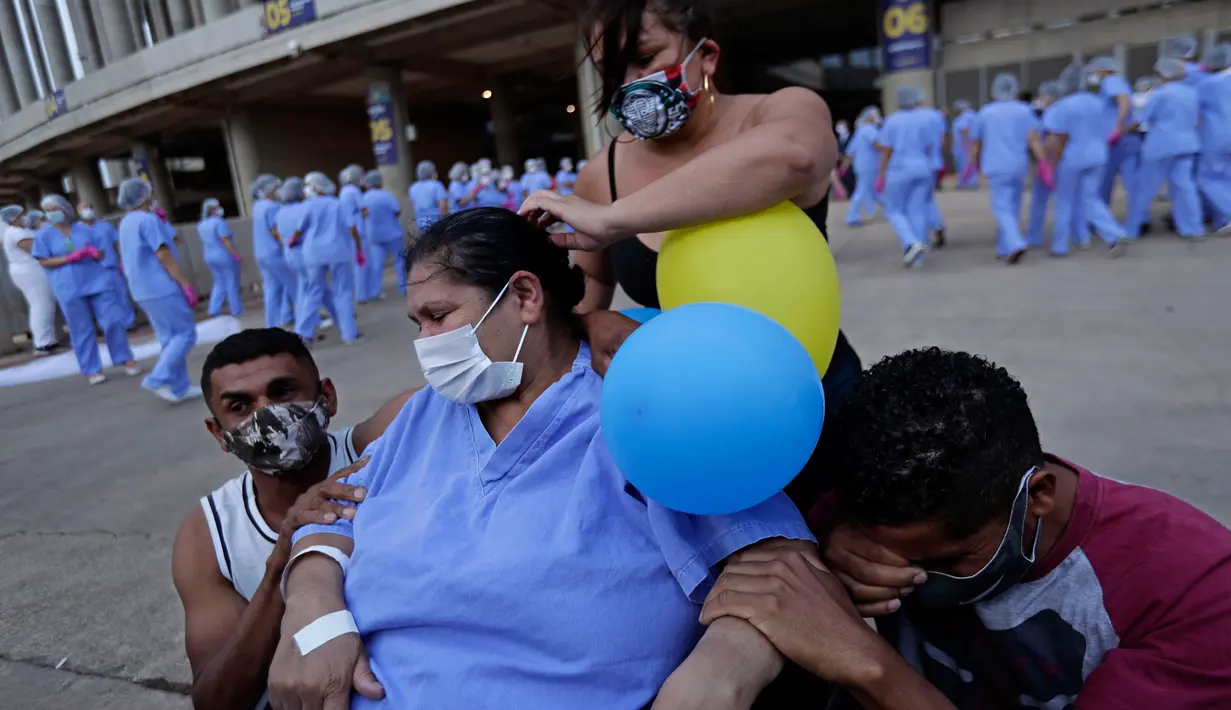Helena Elvira (63) menerima pelukan dari anak-anaknya saat keluar dari rumah sakit di Stadion Nasional Mane Garrincha di Brasilia, Brasil, Kamis (15/10/2020). Rumah sakita darurat tersebut memulangkan tiga pasien COVID-19 terakhir setelah dinyatakan sembuh (AP Photo/Eraldo Peres)