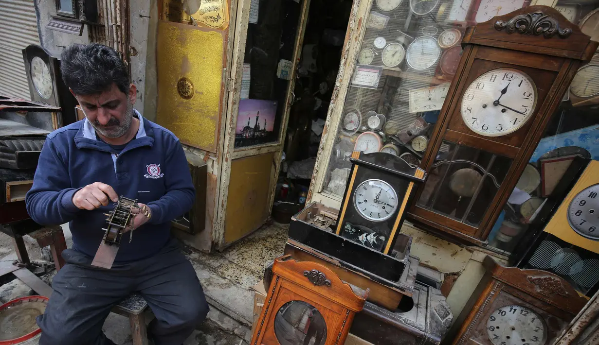 Hussein Mahmud (45) asal Irak saat memperbaiki jam kuno di gudangnya di daerah Maidan Baghdad (20/2). (AFP Photo/Ahmad Al-Rubaye)