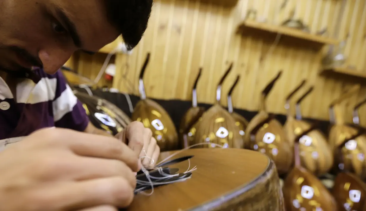 Pekerja memasang senar melengkapi proses pembuatan alat musik Oud di sebuah rumah produksi di Damaskus, Suriah (17/7). Biasanya Oud ini dimainkan sambil diiringi gendang. (AFP Photo/Louai Beshara)