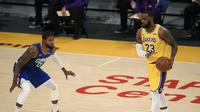Pemain LA Lakers, LeBron James, mengontrol bola dengan dikawal pemain LA Clippers, Paul George, pada laga pembuka NBA 2020/2021, di Staples Center, Rabu (23/12/2020) pagi WIB. (AFP/Harry Haw)