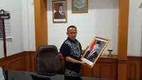 Wakil Ketua DPRD dari Fraksi PDIP, Rojab Asyari, menurunkan bingkai foto resmi Wakil Presiden Gibran Rakabuming Raka. (Liputan6.com/Fira Syahrin)
