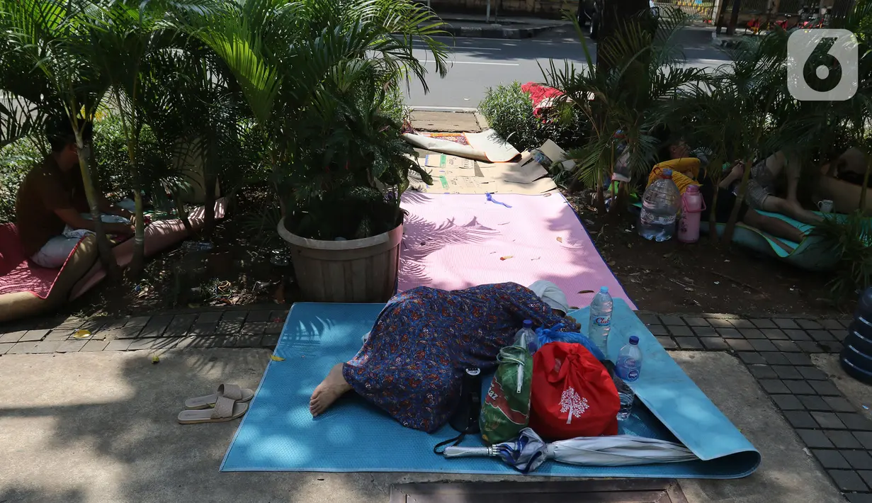 Pencari suaka beristirahat di trotoar kantor UNHCR, Jalan Kebon Sirih, Jakarta, Sabtu (1/5/2021). Para pencari suaka itu menuntut Komisi Tinggi PBB untuk Pengungsi (UNHCR) meminta kejelasan atas status dan memperhatikan nasib mereka selama hidup di Indonesia. (Liputan6.com/Herman Zakharia)