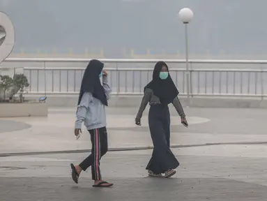 Dua wanita mengenakan masker saat mengunjungi alun-alun Kabupaten Siak, Riau, Kamis (12/9/2019). Asap pekat kebakaran lahan gambut tersebut selain mengganggu kesehatan serta mencemari udara sehingga kualitasnya turun ke status tidak sehat. (Liputan6.com/Faizal Fanani)