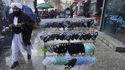 Masker untuk membantu mencegah penyebaran virus corona dijual di sebuah pasar, di Kabul, 7 Februari 2022. Lima dari 38 rumah sakit perawatan COVID yang pernah beroperasi di Afghanistan terpaksa ditutup karena kekurangan dokter, obat-obatan dan bahkan pemanas. (AP Photo/Hussein Malla)