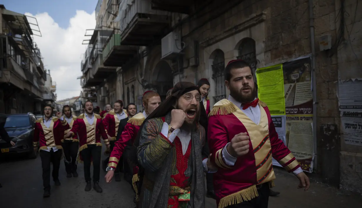 Warga Yahudi Ultra-Ortodoks merayakan setelah minum alkohol selama hari libur Yahudi Purim, di lingkungan ultra-Ortodoks Mea Shearim di Yerusalem, Minggu (28/2/2021). Hari libur Purim Yahudi memperingati keselamatan orang Yahudi dari genosida di Persia kuno, seperti yang diceritakan dalam Kitab Este