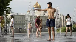 Seorang pria mengisi botol di air mancur sebuah taman di sebelah tanggul Sungai Moskow, di Moskow, Rusia, Rabu (14/7/2021). Cuaca panas di Moskow berlanjut dengan suhu mencapai 34 derajat Celcius (93,2 Fahrenheit) dalam sehari. (AP Photo/Pavel Golovkin)
