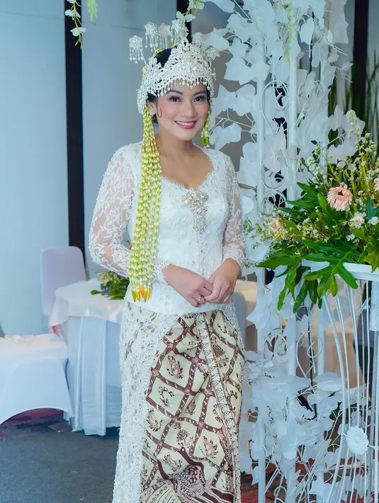 Titi Kamal jadi pengantin Sunda. Ia tampil elegan luar biasa dengan kebaya putih dan padu padan kain batik yang serasi, lengkap dengan siger dan ronce bunga melatinya. [Foto: Instagram/titi_kamall]