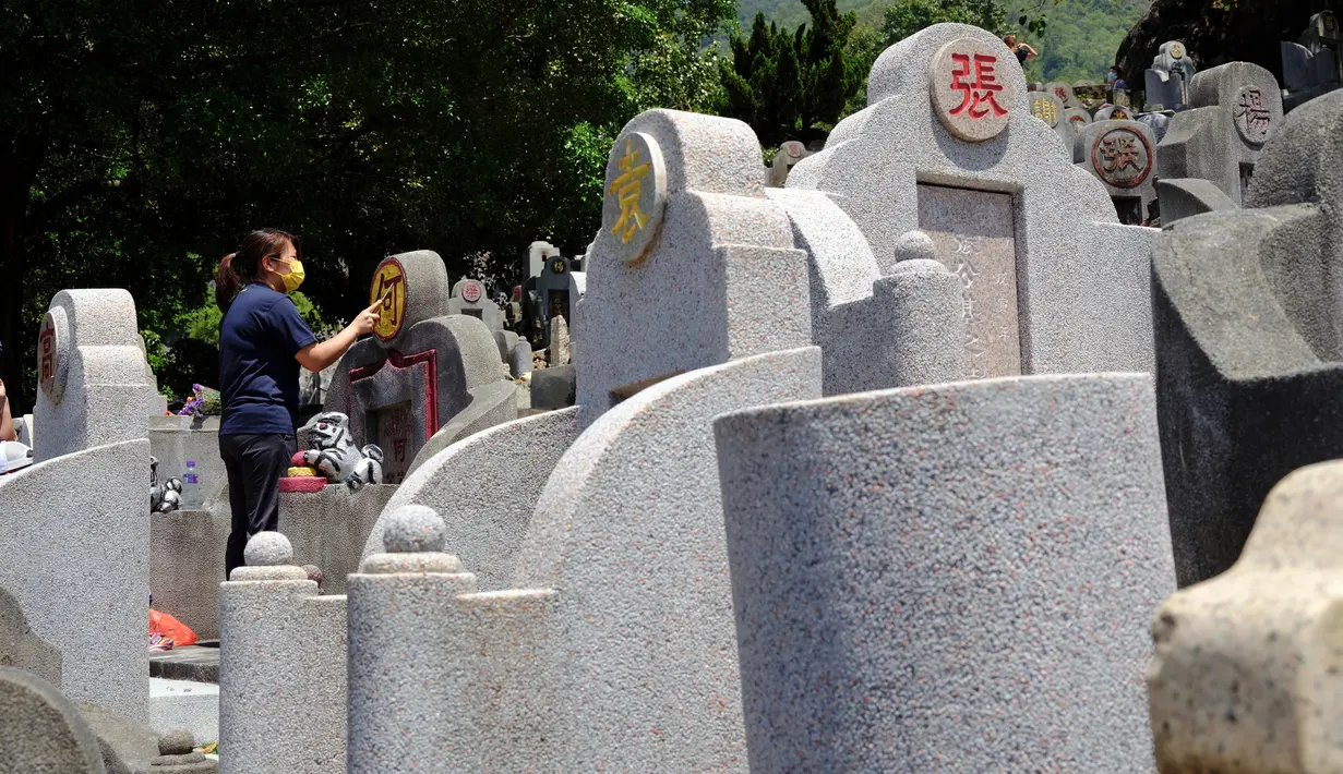 Seorang wanita membersihkan makam kerabat saat Festival Ching Ming atau Hari Sapu Makam di Hong Kong, Selasa (5/4/2022). Ribuan warga Hong Kong memberi hormat kepada leluhur dan kerabat mereka selama festival tahunan ini. (AP Photo/Vincent Yu)