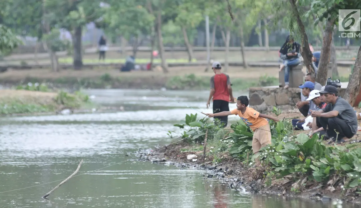Warga memancing di danau Taman Cempaka, Cipayung, Jakarta Timur, Minggu (7/7/2019). Selain dikelilingi pepohonan yang rindang, taman ini dilengkapi berbagai sarana seperti trek jogging, wahana bermain anak, hingga danau buatan yang ramai didatangi warga untuk memancing. (merdeka.com/Iqbal S Nugroho)
