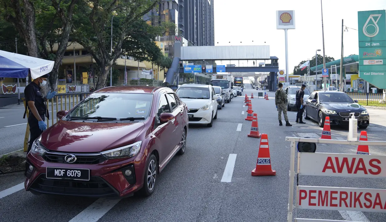 Polisi memeriksa penumpang di kendaraan pada hari pertama Perintah Kontrol Gerakan Penuh (MCO) di Kuala Lumpur, Malaysia (1/6/2021). Penguncian kedua dilakukan untuk mengatasi pandemi yang memburuk yang telah menempatkan sistem perawatan kesehatannya di ambang kehancuran. (AP Photo/Vincent Thian)