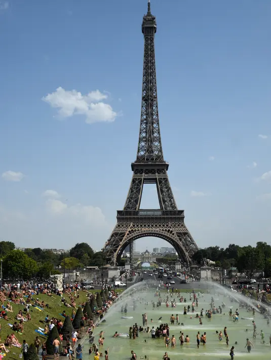 Turis dan warga menyejukkan diri dan berjemur di kolam Trocadero Fountains (air mancur Trocadero) dekat Menara Eiffel di Paris, Kamis (25/7/2019). Gelombang panas di Eropa mencapai puncaknya, bahkan suhu di ibu kota Prancis mencapai di atas 41 derajat Celcius. (Bertrand GUAY / AFP)