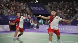 Pemain ganda putri Indonesia, Apriyani Rahayu (kanan) berusaha mengembalikan bola saat menghadapi wakil China, Chen Qingchen/Jia Yifan pada laga kedua Grup A nomor ganda putri cabor bulu tangkis Olimpiade Paris 2024 di Porte de la Chapelle Arena, Prancis, Minggu (28/7/2024). (AP Photo/Dita Alangkara)