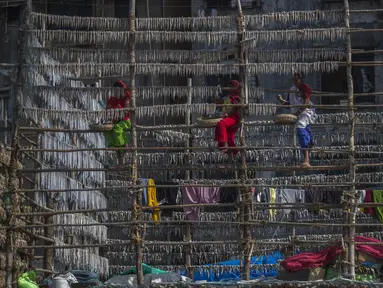 Sejumlah nelayan wanita menggantung ikan di tiang bambu untuk dijemur di koloni nelayan di Mumbai, India, Rabu (29/12/2021). (AP Photo/Rafiq Maqbool)
