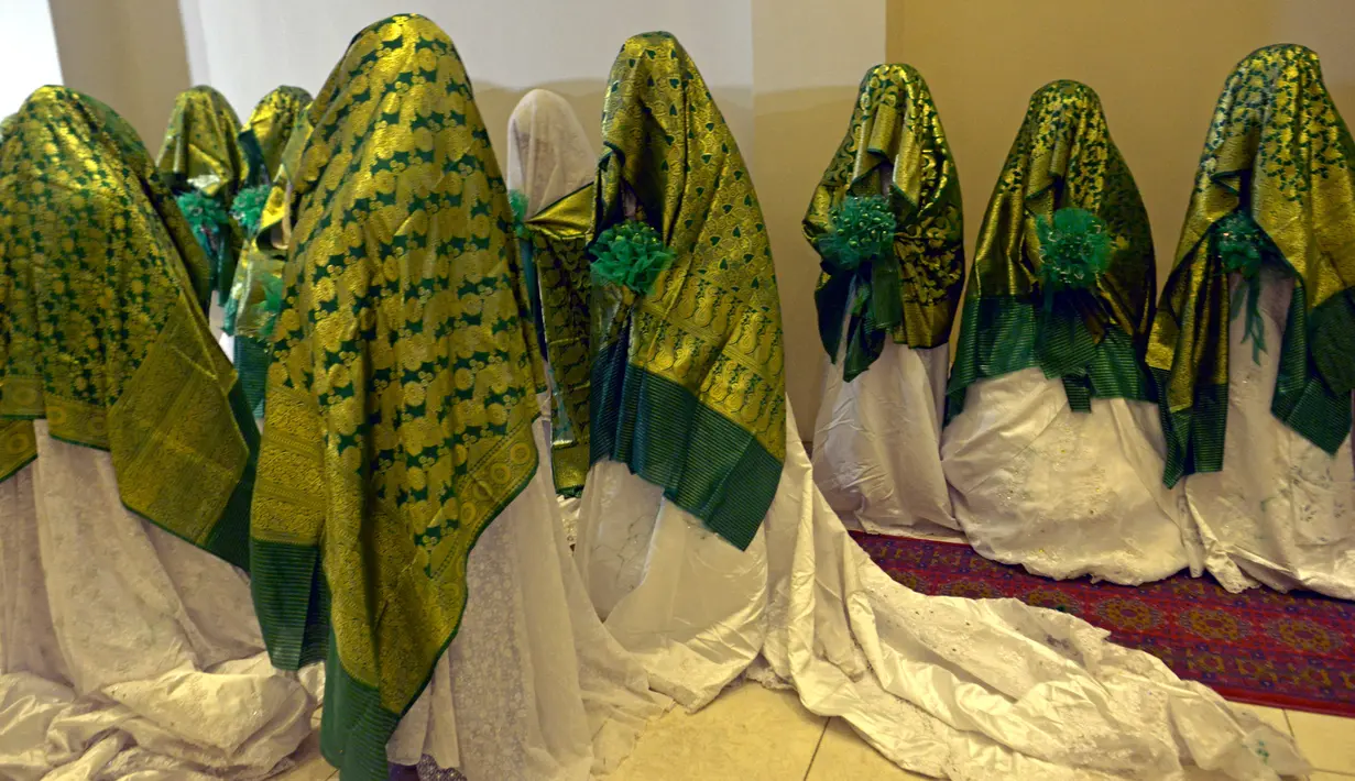 Pengantin menunggu dimulainya upacara pernikahan massal di Kabul, Afghanistan, 13 Juni 2022. Puluhan wanita Afghanistan yang disembunyikan dalam selendang hijau tebal dinikahkan dalam pernikahan massal yang ketat di Kabul. (Sahel ARMAN/AFP)
