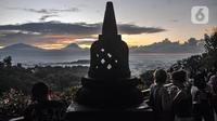 Wisatawan menikmati matahari terbit atau sunrise dengan latar belakang Candi Borobudur di Punthuk Setumbu, Karangrejo, Magelang, Jawa Tengah, Senin (16/5/2022). Punthuk Setumbu menjadi destinasi favorit di Jawa Tengah, terlebih saat libur Waisak yang terkenal dengan keindahan alam Candi Borobudur dan sekitarnya saat matahari terbit. (merdeka.com/Iqbal S. Nugroho)