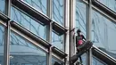 Alain Robert yang dijuluki 'French Spiderman' memanjat gedung pencakar langit Cheung Kong Center di Hong Kong, Jumat (16/8/2019). Selama pendakian, Alain Robert memasang spanduk yang menampilkan bendera Hong Kong dan China. (Lillian SUWANRUMPHA/AFP)