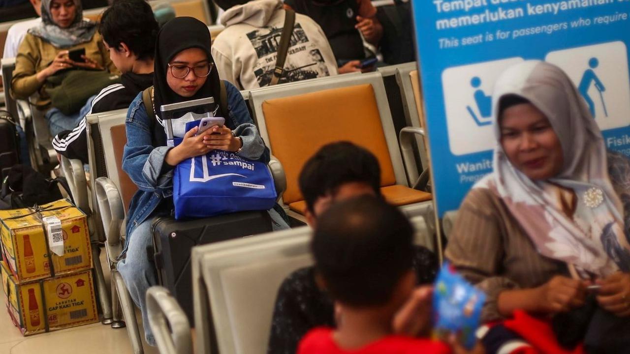 Seorang penumpang wanita menyibukkan diri dengan bermain ponsel saat menunggu keberangkatan kereta di Stasiun Pasar Senen, Jakarta, Rabu (3/4/2024). Foto:  Liputan6.com / Angga Yuniar