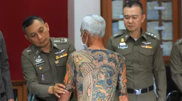 Petugas menunjukkan tato Mantan bos Yakuza asal Jepang, Shigeharu Shirai di sebuah kantor polisi saat konferensi pers di Lopburi, Thailand, Kamis, (11/1). Pria 72 tahun ini ditangkap setelah 14 tahun menjadi buronan. (AP Photo)