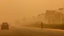 Seorang pria terlihat saat sepanjang jalan raya yang diselimuti debu tebal selama terjangan badai pasir di Kuwait City, Kuwait, pada 17 Juni 2021. Terjangan badai pasir ini membuat jarak pandang atau visibilitas di beberapa daerah turun hingga kurang dari 100 meter. (AFP/YasserAl-Zayyat)