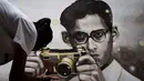 Seorang mahasiswa seni di Thailand melukis potret raja Bhumibol Adulyadej yang sedang memegang kamera, Bangkok, Senin (17/10). Pria yang bergelar Raja Rama IX itu memiliki kecintaan terhadap musik jazz dan dunia fotografi. (Reuters/Athit Perawongmetha)