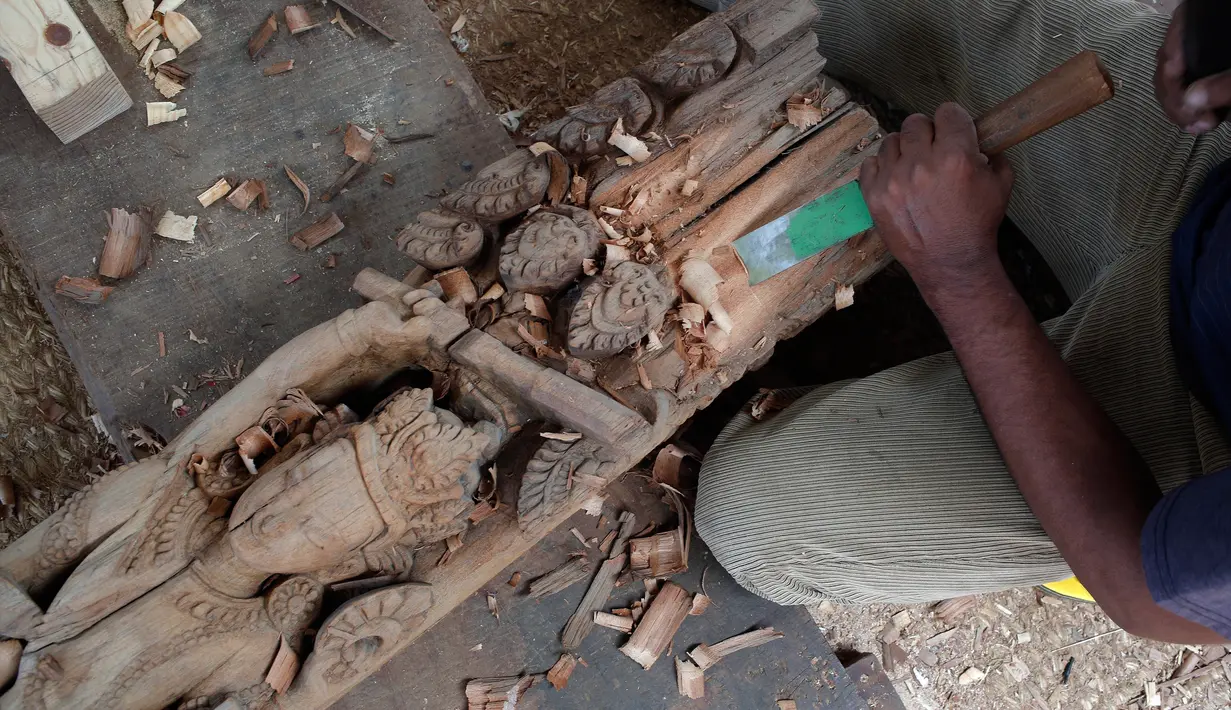 Seorang pengrajin kayu dari komunitas etnis Newar memahat kayu di Lalitput, Nepal (19/7). Komunitas pengrajin kayu ini memperbaiki pintu dan jendela kayu yang rusak akibat gempa Nepal menjadi kayu ukiran yang menawan. (AP Photo/Niranjan Shrestha)