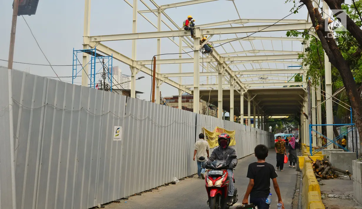 Warga melintas di antara proyek pembangunan "Skybridge" di Tanah Abang, Jakarta, Selasa (28/8). Pembangunan jembatan yang menghubungkan Stasiun Tanah Abang-Pasar Blok G Tanah Abang itu ditargetkan selesai pada Oktober 2018. (Liputan6.com/Herman Zakharia)