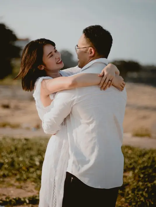 Gaya mesra Laura Basuki dan Leo Sanjaya. Laura Basuki tampil cantik dengan sebuah dress lengan pendek berwarna putih yang simpel dan chic, sedangkan Leo Sandjaja mengenakan kemeja putih lengan panjang dan celana pendek berwarna hitam. [Foto: Instagram/laurabas]