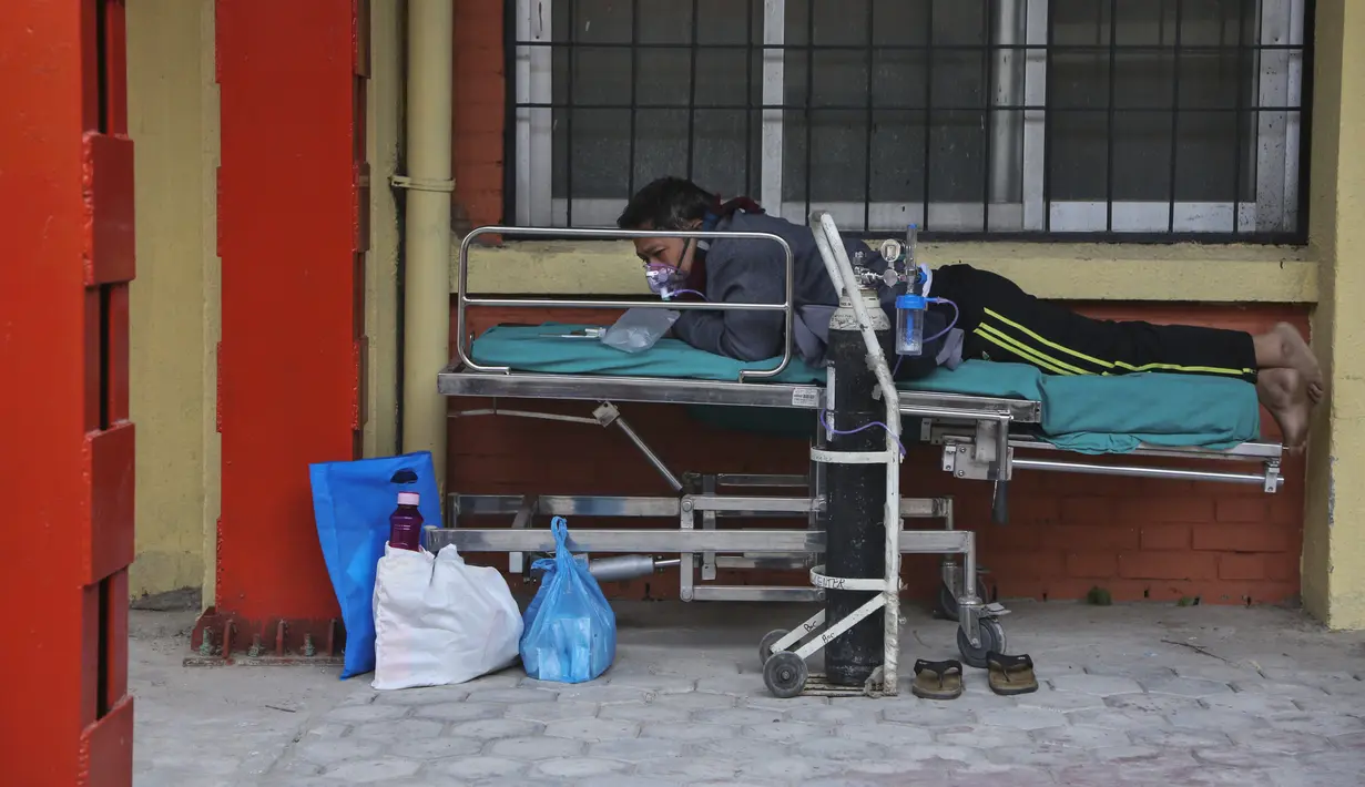 Seorang pasien COVID-19 menerima oksigen di koridor bangsal gawat darurat rumah sakit di Kathmandu, Rabu (5/5/2021). Lockdown di ibu kota Kathmandu dan distrik sekitarnya diperpanjang ketika negara Himalaya mencatat infeksi harian COVID-19 dan kematian tertinggi. (AP Photo/Niranjan Shrestha)