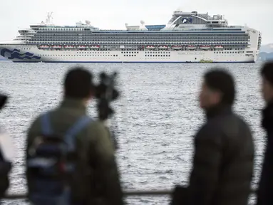 Seorang kru TV memfilmkan sebuah kapal pesiar Diamond Princess berlabuh di Pelabuhan Yokohama di Yokohama, Tokyo (4/2/2020). Otoritas Kesehatan Jepang mengkarantina 3.700 orang di dalam sebuah kapal pesiar setelah satu penumpang dinyatakan positif terkena virus corona.  (AP Photo/Eugene Hoshiko)