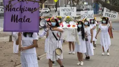 Rombongan teater Vichama melakukan prosesi kamar mayat berjudul "Kami Ingin Diri Sendiri Hidup!" sambil membawa tubuh tiruan dan menampilkan tanda-tanda kiasan pada malam Hari Anti Kekerasan Terhadap Perempuan di Villa El Salvador, Lima, Peru, 24 November 2021. (Cris BOURONCLE/AFP)