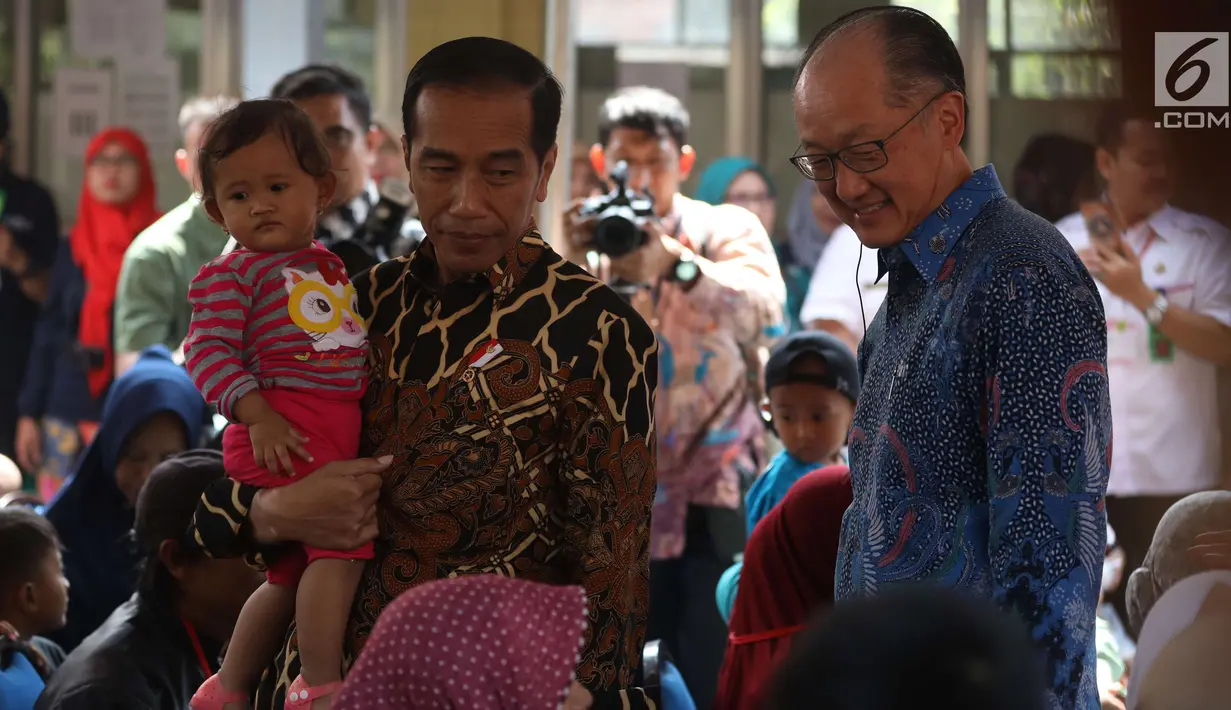 Presiden Joko Widodo (Jokowi) menggendong balita sambil mengajak Presiden Bank Dunia Jim Yong Kim blusukan ke Desa Tangkil, Kecamatan Caring, Bogor, Rabu (4/7). Keduanya meninjau Posyandu dan PAUD di dekat SDN 01 Tangkil. (Liputan6.com/Angga Yuniar)