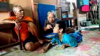 Difabel ganda, M Ali saat disuapi makan oleh ibunya Fatima di depan ayahnya Rusli, di Kabupaten Musi Banyuasin Sumsel (Liputan6.com / Nefri Inge)
