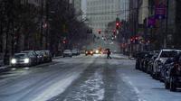 Seorang pejalan kaki menggunakan payung saat melintasi Liberty Avenue saat salju mulai turun selama badai musim dingin yang akan berdampak pada wilayah tersebut di pusat Kota Pittsburgh, Amerika Serikat, 16 Januari 2022. (Alexandra Wimley/Pittsburgh Post-Gazette via AP)