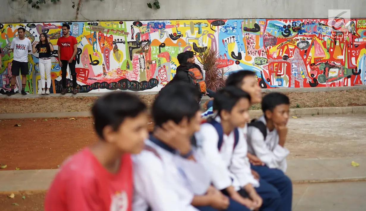 Warga duduk dengan latar belakang Mural menghiasi tembok dalam acara Mural Cikini Project #1 di Taman Plaza Teater Besar, Taman Ismail Marzuki, Jakarta, Jumat (23/8/2019). Project #1/Mural Cikini yang diikuti oleh 4 seniman yang digelar dalam rangka menata estetika. (Liputan6.com/Faizal Fanani)