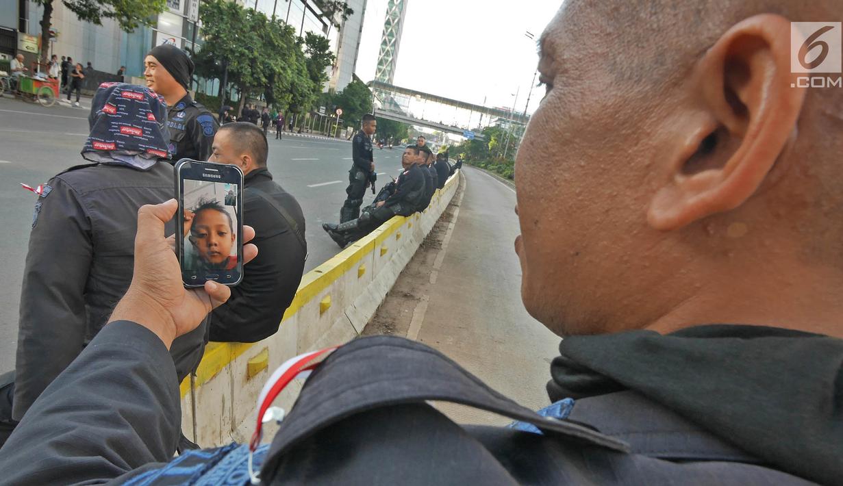 Seorang anggota Brimob melakukan panggilan video dengan anaknya disela penjagaan di kawasan MH Thamrin, Jakarta, Jumat (24/5/2019). Usai kerusuhan 22 Mei 2019, penjagaan di kawasan jalan MH Thamrin sampai Jumat, 24 Mei 2019 masih terus dilakukan oleh aparat kepolisian. (Liputan6.com/Herman Zakharia)