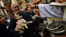 Seorang pria membawa anjingnya untuk diberkati pada peringatan Hari santo Antonius di luar gereja San Nicolas, Spanyol, Kamis (17/1). Pada perayaan tahunan itu, para pemilik membawa hewan peliharaan untuk diberkati oleh pastor. (AP/Alvaro Barrientos)