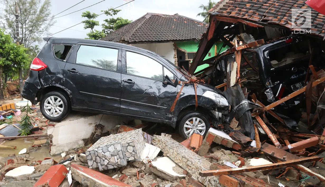 Dua unit mobil tertimbun reruntuhan rumah yang rusak setelah tsunami menerjang kawasan Anyer, Banten, Minggu (23/12). Tsunami menerjang pantai di Selat Sunda, khususnya di daerah Pandenglang, Lampung Selatan, dan Serang. (Liputan6.com/Angga Yuniar)