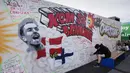 Orang-orang menulis harapan baik pada mural untuk gelandang timnas Denmark Christian Eriksen di dinding fanzone di Kopenhagen, Senin (14/6/2021). Eriksen mengalami serangan jantung dan sempat tak sadarkan diri saat memperkuat timnas Denmark vs Finlandia di Euro 2020. (AP Photo/Martin Meissner)