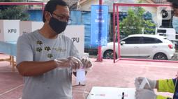 Pemiilih mengenakan sarung tangan plastik saat menggunakan hak suaranya dalam Pilkada Tangerang Selatan di TPS 23 Pondok Jagung Timur, Rabu (9/12/2020). Menggunakan masker hingga memakai sarung tangan plastik menjadi hal wajib saat melakukan pencoblosan di Pilkada 2020. (Liputan6.com/Angga Yuniar)