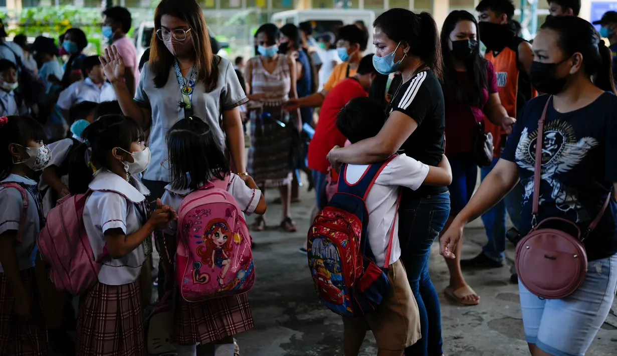 Seorang siswa memeluk penjemputnya di sebuah sekolah umum di Kota Quezon, Filipina pada Rabu (2/11/2022). Jutaan siswa kembali ke sekolah umum di seluruh Filipina saat pemerintah memberlakukan kembali pembelajaran di kelas secara tatap muka setelah lebih dari dua tahun lockdown akibat pandemi virus corona. (AP Photo/Aaron Favila)