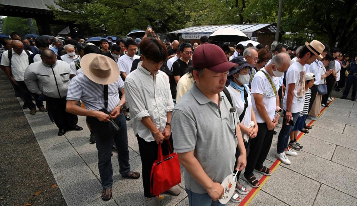 Orang-orang berhenti sejenak untuk mengheningkan cipta saat mereka mengantre untuk memberikan penghormatan ketika berkunjung ke Kuil Yasukuni di Tokyo, Jepang, Selasa (15/8/2023). Aksi tersebut untuk memperingati 78 tahun penyerahan Jepang kepada Sekutu dalam Perang Dunia II tahun 1945. (Kazuhiro NOGI/AFP)