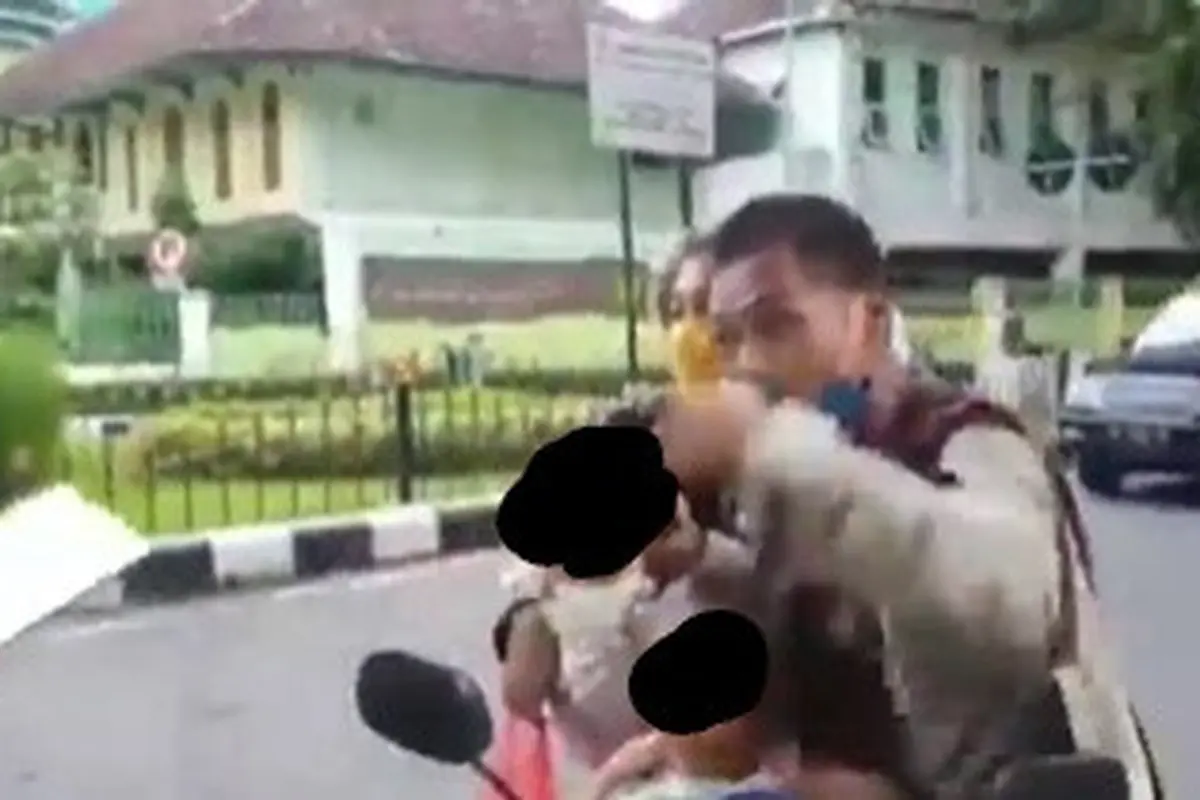 terlihat pasangan suami istri tak mau ditilang petugas kepolisian karena tak menggunakan helm.
