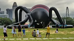 Sejumlah orang melihat balon laba-laba raksasa di kawasan Marina Bay, Singapura, Senin (6/2). Balon buatan seniman Singapura Jackson Tan tersebut dibuat untuk memeriahkan acara festival cahaya di Singapura. (AFP PHOTO / ROSLAN RAHMAN)