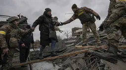 Prajurit Ukraina membantu seorang perempuan yang membawa seekor anjing kecil melintasi Sungai Irpin di jalur improvisasi sambil membantu orang-orang yang melarikan diri dari kota Irpin, Ukraina, 5 Maret 2022. (AP Photo/Vadim Ghirda)