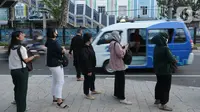 Para calon penumpang antre menunggu giliran untuk naik transportasi layanan angkutan umum JakLingko di Stasiun Klender Baru, Pondok Kopi, Jakarta, Senin (19/2/2024). (merdeka.com/Imam Buhori)