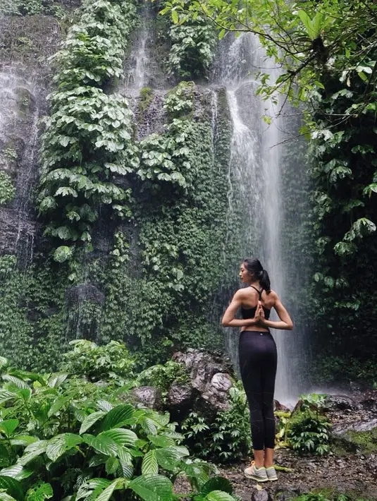 Dan kali ini Liza Elly tampak sedang melakukan Yoga di alam terbuka. Di bawah pancuran air terjun, Liza Elly memakai celana panjang hitam dan tanktop serta sneakers putihnya.  (Instagram/lizaellyp)