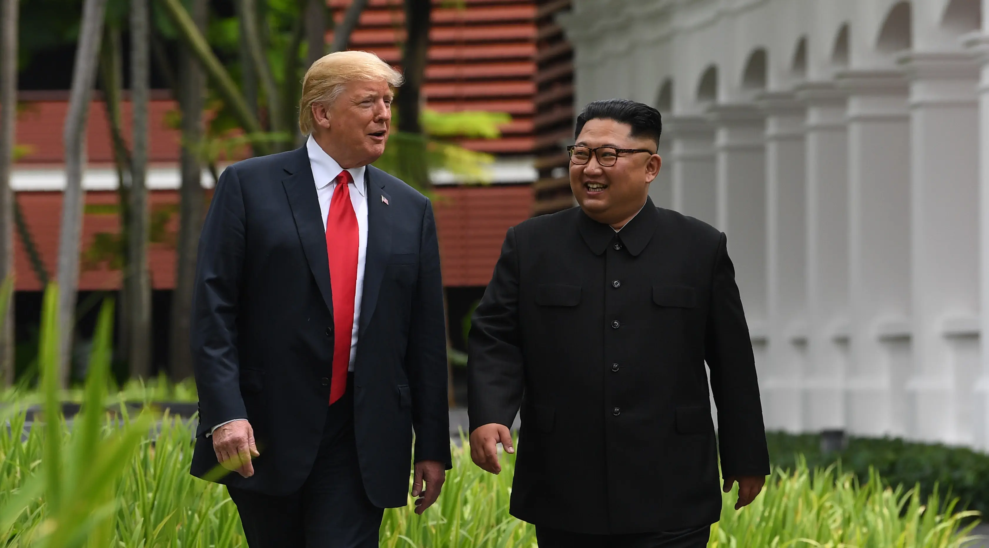 Keakraban Presiden AS Donald Trump (kiri) dengan Pemimpin Korea Utara Kim Jong-un saat berjalan di taman Hotel Capella, Pulau Sentosa, Singapura, Selasa (12/6). Trump dan Kim bertemu untuk membicarakan upaya denuklirisasi Korut. (Anthony Wallace/Pool/AFP)