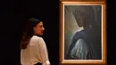 Karyawan rumah lelang Bonhams berpose dekat lukisan seorang putri Nigeria bernama Tutu di London, Inggris pada 7 Februari 2018. Lukisan yang kerap disebut ‘Mona Lisa dari Afrika’ itu terjual dalam sebuah lelang pada 28 Februari 2018. (BEN STANSALL/AFP)