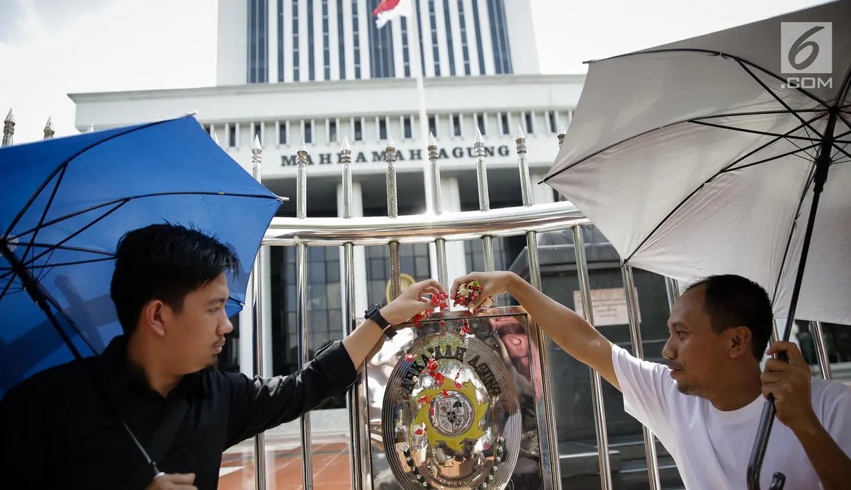 Massa saat menggelar aksi damai di depan Mahkamah Agung, Jakarta, Rabu (7/6). Dalam aksinya mereka menaburkan bungan pada payung sebagai bentuk simbol kekhawatiran matinya keadilan dan penegakan hukum. (Liputan6.com/Faizal Fanani)