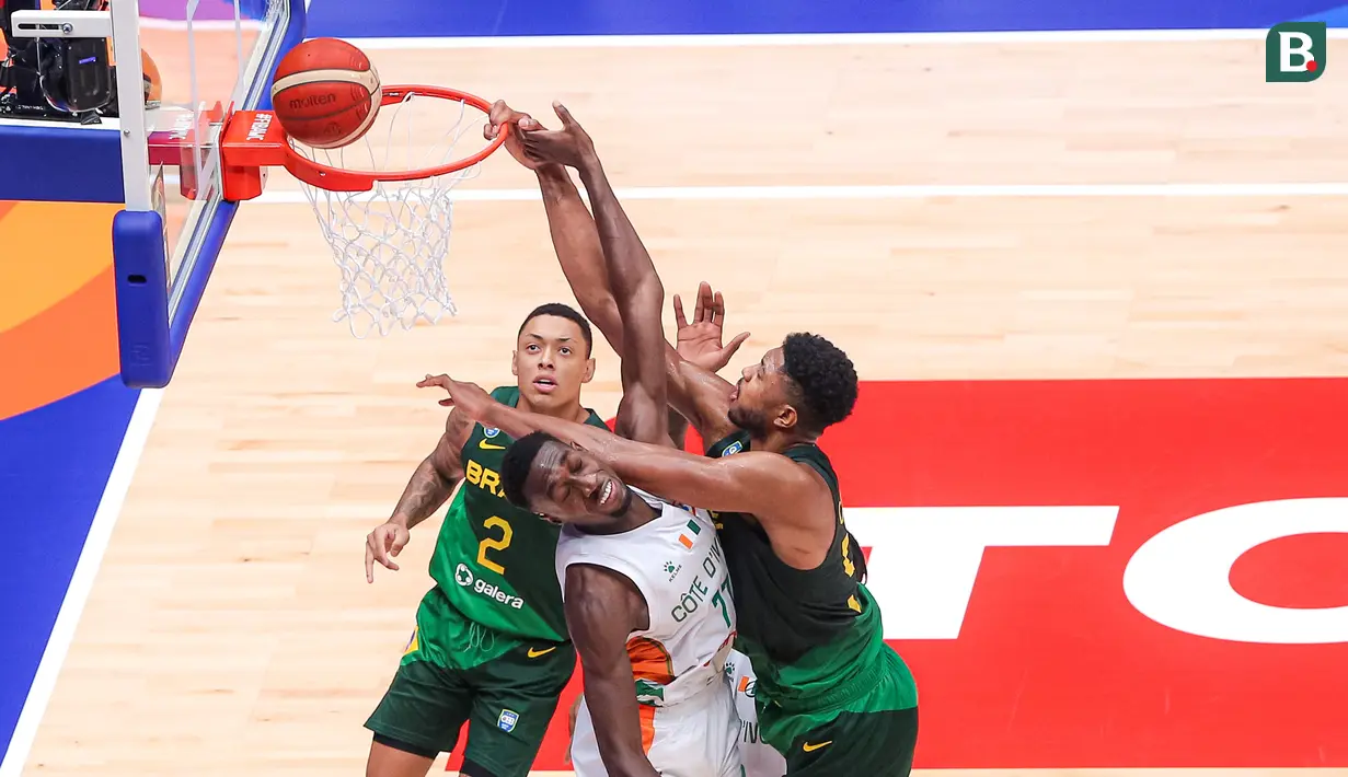 Pebasket Brasil, Bruno Caboclo (kanan) berusaha mencetak poin dihalangi pebasket Pantai Gading, Jean Philippe Dally (tengah) pada laga ketiga Grup G Piala Dunia FIBA 2023 di Indonesia Arena, Senayan, Jakarta, Rabu (30/08/2023). Brasil menang dengan skor 89-77. (Bola.com/Bagaskara Lazuardi)